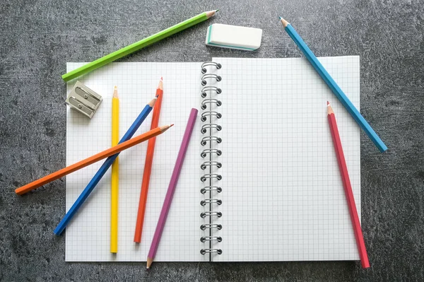 平面放置空白的开放式螺旋笔记本 带有复制空间 彩色蜡笔 锐利和橡皮擦 用于创造性工作 学习或学校在灰色桌子上 高角度视图 选择焦点 — 图库照片