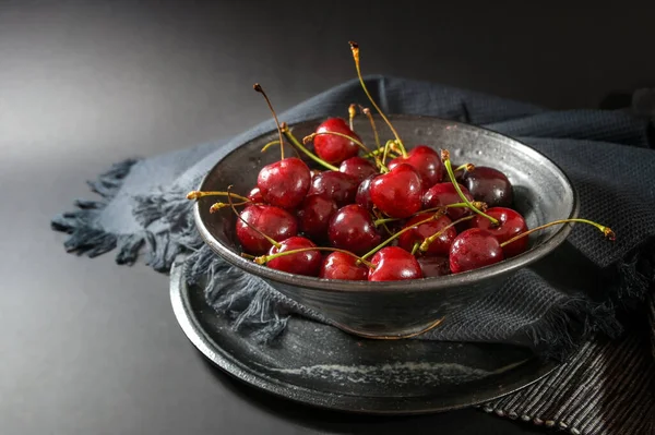 新鲜的红色樱桃在一个带有餐巾和盘子的乡村陶瓷碗中 深色灰色背景 健康的夏季小吃 复制空间 选定的焦点 狭窄的田野深度 — 图库照片
