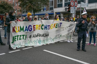 Lubeck, Almanya, 24 Eylül 2021: Renkli bir Alman sloganıyla protesto pankartı taşıyan gençler, yani İklim Adaleti Şimdi, küresel Gelecek Cumaları gösteri yürüyüşü için düzenlenen mitingde,