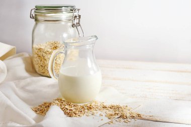 Vejetaryen yulaf sütü, açık ahşap bir masada cam sürahi içinde hayvansal süt ürünleri olmadan sağlıklı bir alternatif, kopyalama alanı, seçilmiş odak, dar alan derinliği