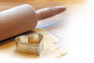 baking a heart with rolling pin and cookie cutter,  blurred to w clipart