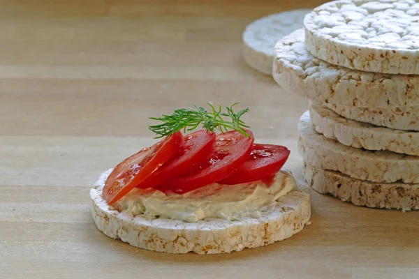 Pila di torte di riso, una con pomodori su una tavola di legno , — Foto Stock