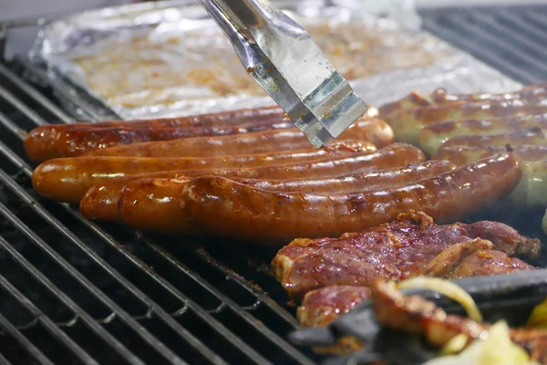 Embutidos fritos y carne a la parrilla en un mercado navideño —  Fotos de Stock