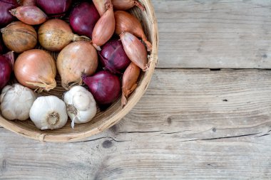 soğan ve sarımsak ahşap arka plan üzerinde bir sepet içinde
