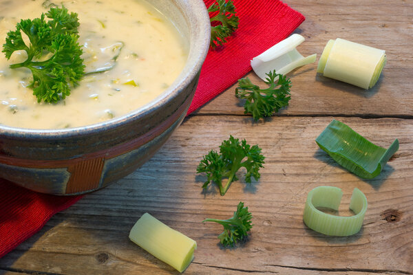 creme sauce in a bowl with fresh leeks and herbs on  rustic wood
