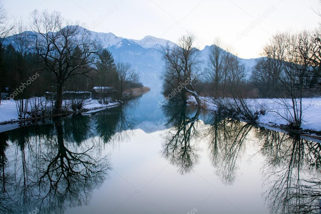 winter trees with reflection in a lake, mountains in the backgro