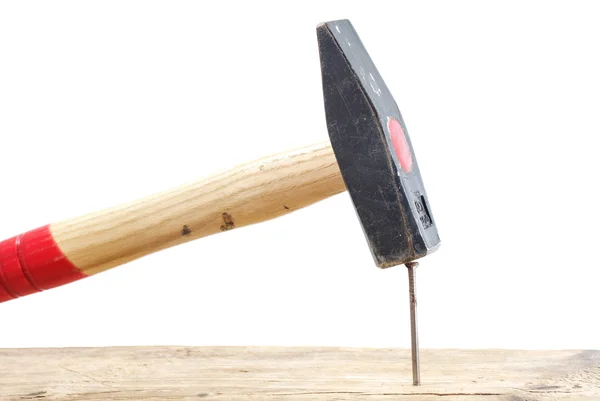 Marteau frappant un clou dans une planche en bois, isolé — Photo