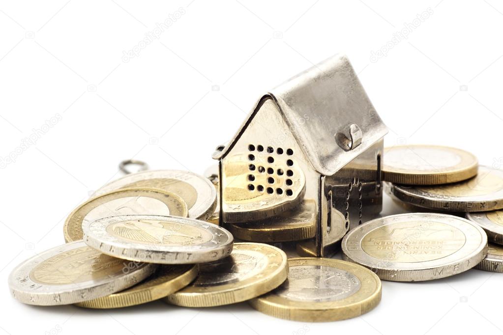 real estade background, little house in a heap of coins isolated