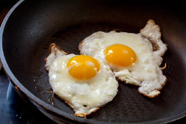 Two fried eggs in a black pan — Stock Photo, Image