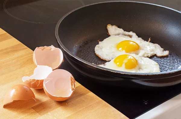 Huevos fritos en una sartén y cáscaras de huevo — Foto de Stock