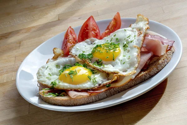 Pane con prosciutto e uovo fritto guarnire con erba cipollina su un piatto — Foto Stock