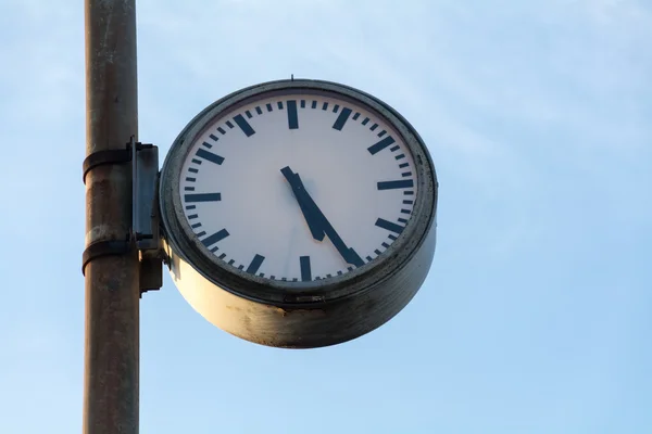 Grande vieille horloge à un poteau rouillé contre le ciel bleu — Photo