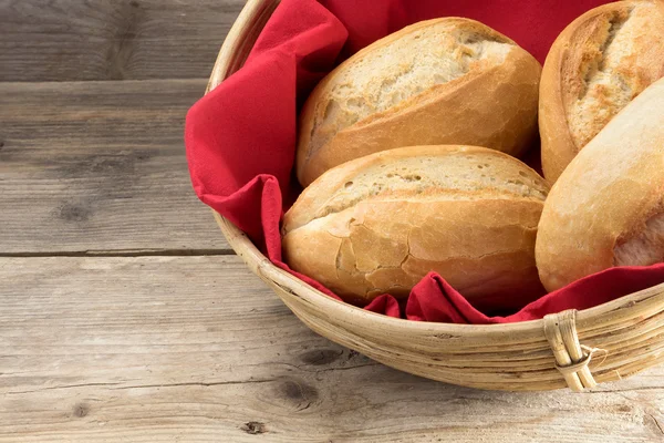 Bread rolls in a basket whith red napkin on old wood — Stock Photo, Image