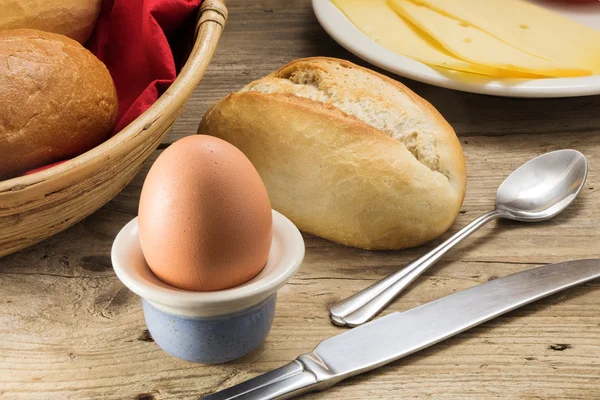 Mesa de desayuno con huevo, queso, panecillos, una cesta con — Foto de Stock