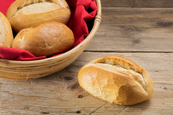 bun and bread rolls in a basket whith red napkin on old wood