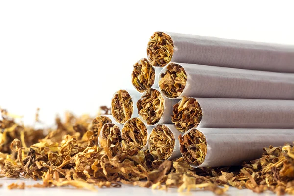 Cigarettes in loose tobacco, close up against white — Stock Photo, Image