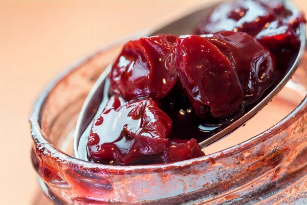 Cuillère prend de la confiture de cerises dans le pot — Photo