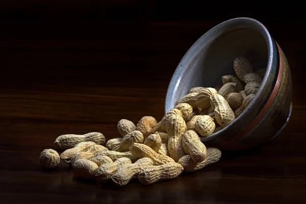 Erdnüsse aus einer Keramikschüssel, dunkler Hintergrund — Stockfoto
