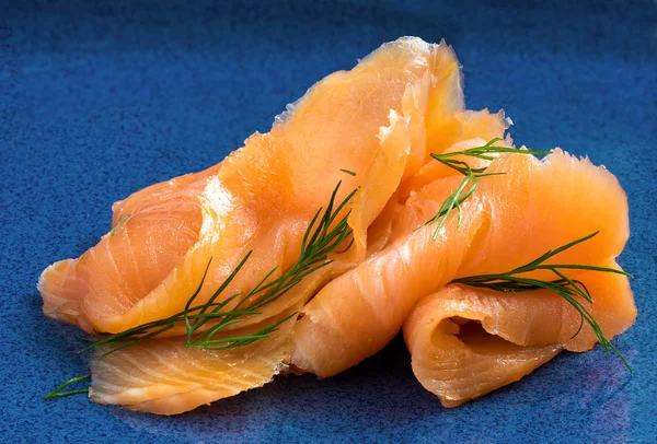 Salmon in slices with dill on a blue plate — Stock Photo, Image