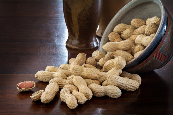 peanuts in shells and rustic ceramic tableware on a dark table