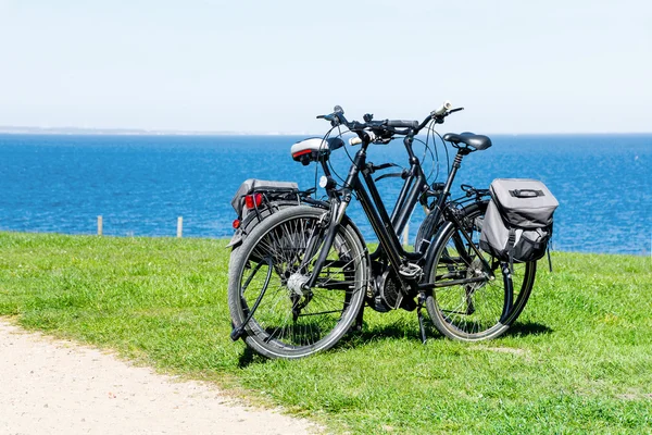 Dos bicicletas estacionadas en el césped en el amplio mar azul — Foto de Stock