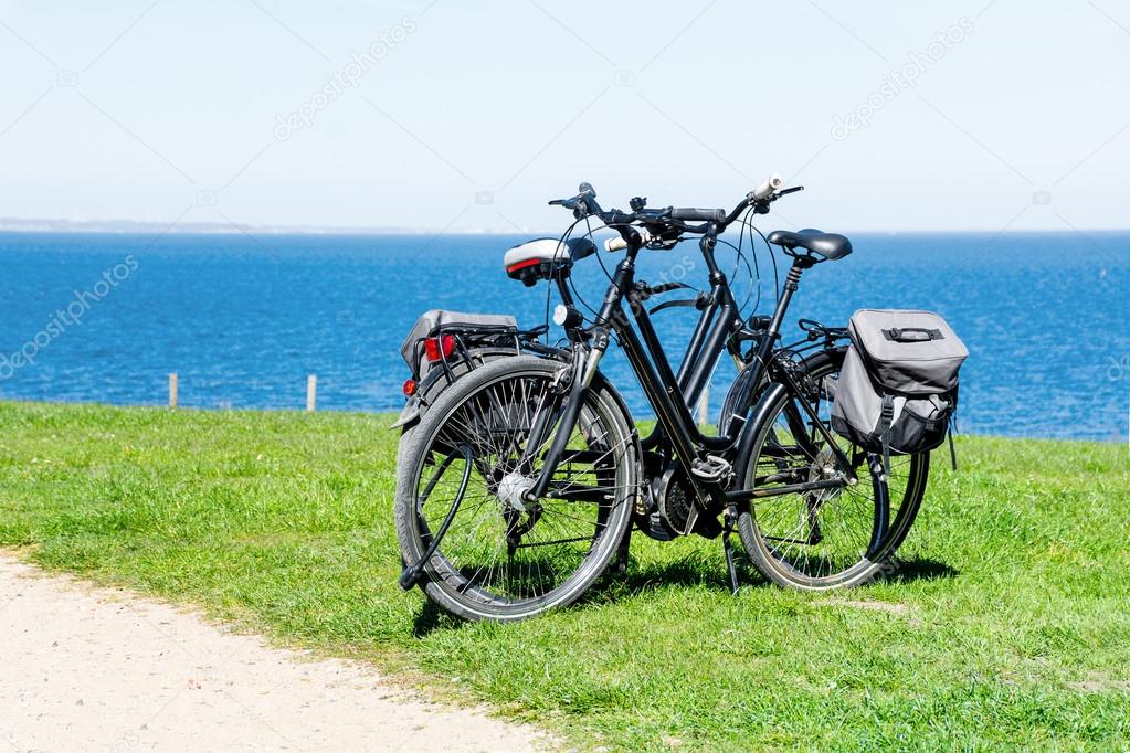 two bikes parked on the lawn at the wide blue sea