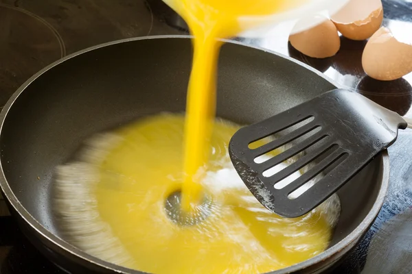 Beaten egg flowing into the pan for scrambled eggs — Stock Photo, Image