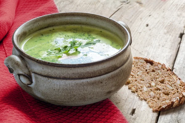 Green vegetable cream soup  in a ceramic bowl on rustic wood — Stock Photo, Image