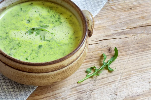 Green vegetable soup in a brown bowl on rustic wood — Stock Photo, Image