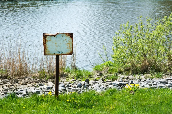 Rostiges Schild am Flussufer — Stockfoto