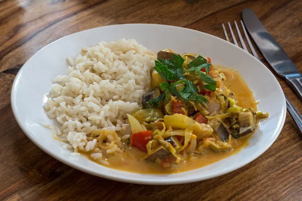Блюдо с овощным карри и рисом на деревянном столе — стоковое фото