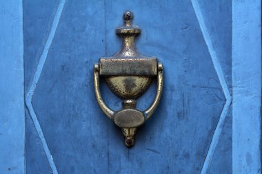 Old doorknocker from brass on a blue  door clipart