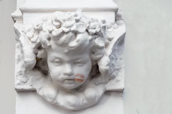 Cherub on a building with a lipstick kiss on his cheek — Stock Photo, Image