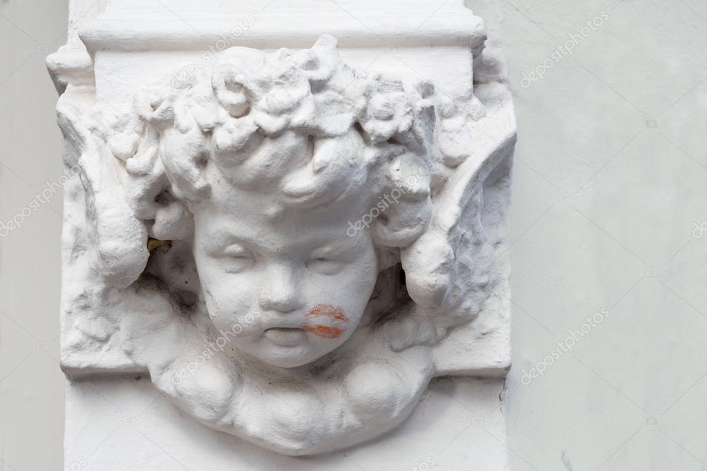cherub on a building with a lipstick kiss on his cheek
