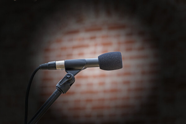 microphone in front of an old blurred brick wall with a light sp