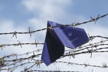 refugee labeled passport folded as a paper plane hanging in a ba