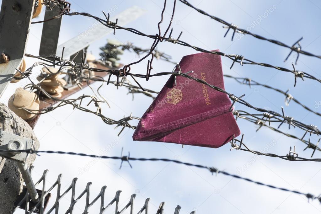 Passport folded as a paper plane hanging in a barbed wire