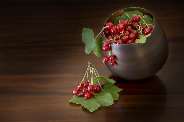 Red currants with leaves in a bowl, dark brown background with c — Stock Photo, Image