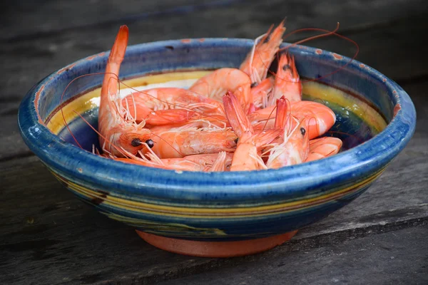 Fresh boiled shrimps in a clay bowl on rustic wood — Stock Photo, Image