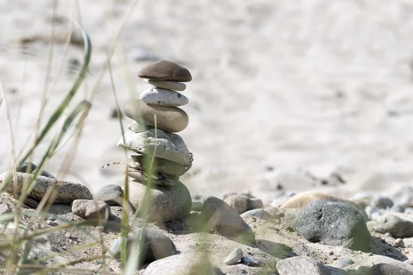 Torre de piedra y plantas en una playa de arena, fondo de vacaciones —  Fotos de Stock