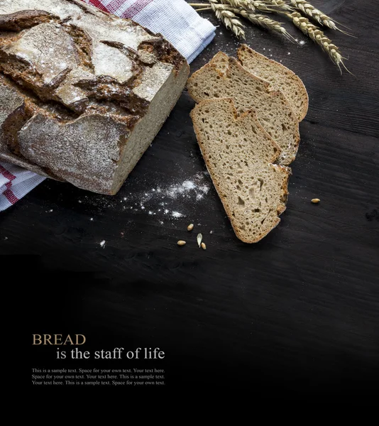 Rustikales Brot und Scheiben auf dunklem Holz verblassen zu schwarz, Beispieltext — Stockfoto