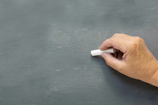 Oudere hand schrijft op een lege schoolbord — Stockfoto