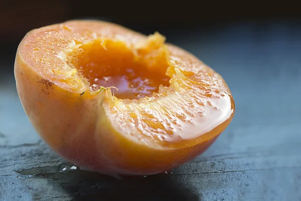 Halved apricot, ripe and juicy on blue wood, closeup — Stock Photo, Image