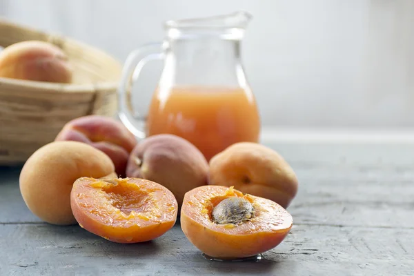 Fresh apricots and juice on light gray wood, copy space in the b — Stock Photo, Image