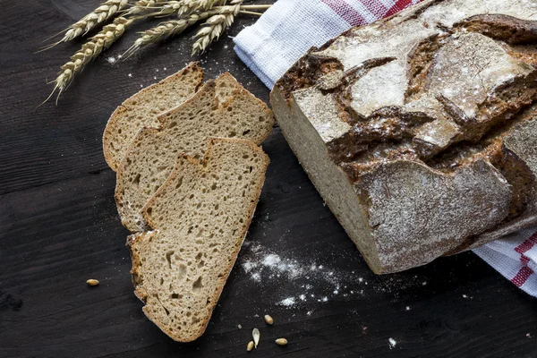 Rusztikus ropogós kenyér és a szeleteket egy sötét barna fa tábla — Stock Fotó
