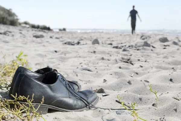 Scarpe da lavoro in spiaggia e un uomo sfocato a piedi — Foto Stock