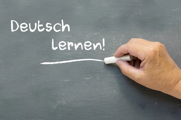 Main sur un tableau avec les mots allemands Deutsch lernen (Apprendre — Photo