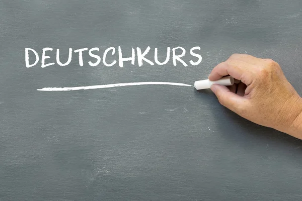 Hand on a chalkboard with the German word Deutschkurs (German co — Stock Photo, Image