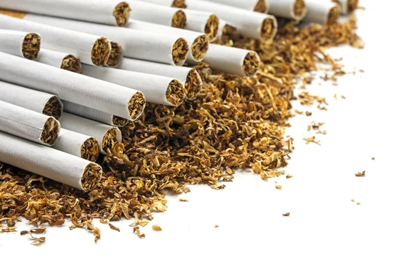 Cigarettes  on a heap of loose tobacco, corner background on whi — Stock Photo, Image