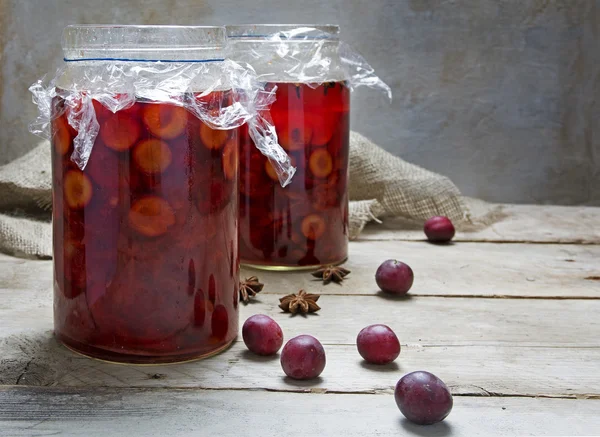 Ciruelas en escabeche con especias en dos vasos sobre una mesa de madera rústica —  Fotos de Stock